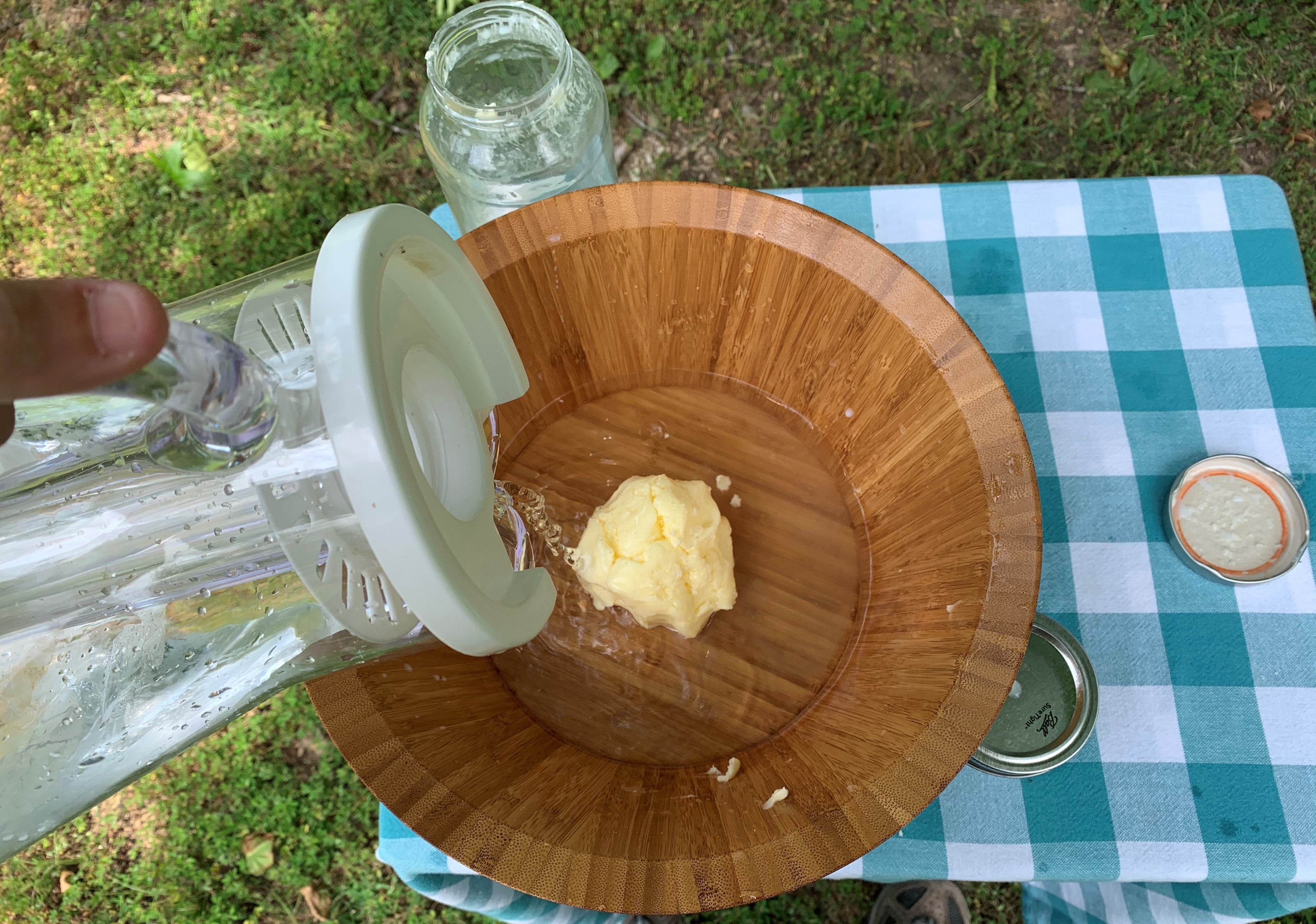 water is being poured over butter that is in a bowl on a table. The liquid coming off the butter is clear